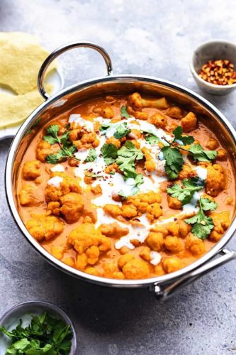 pot of curry with coriander and cream drizzled on top