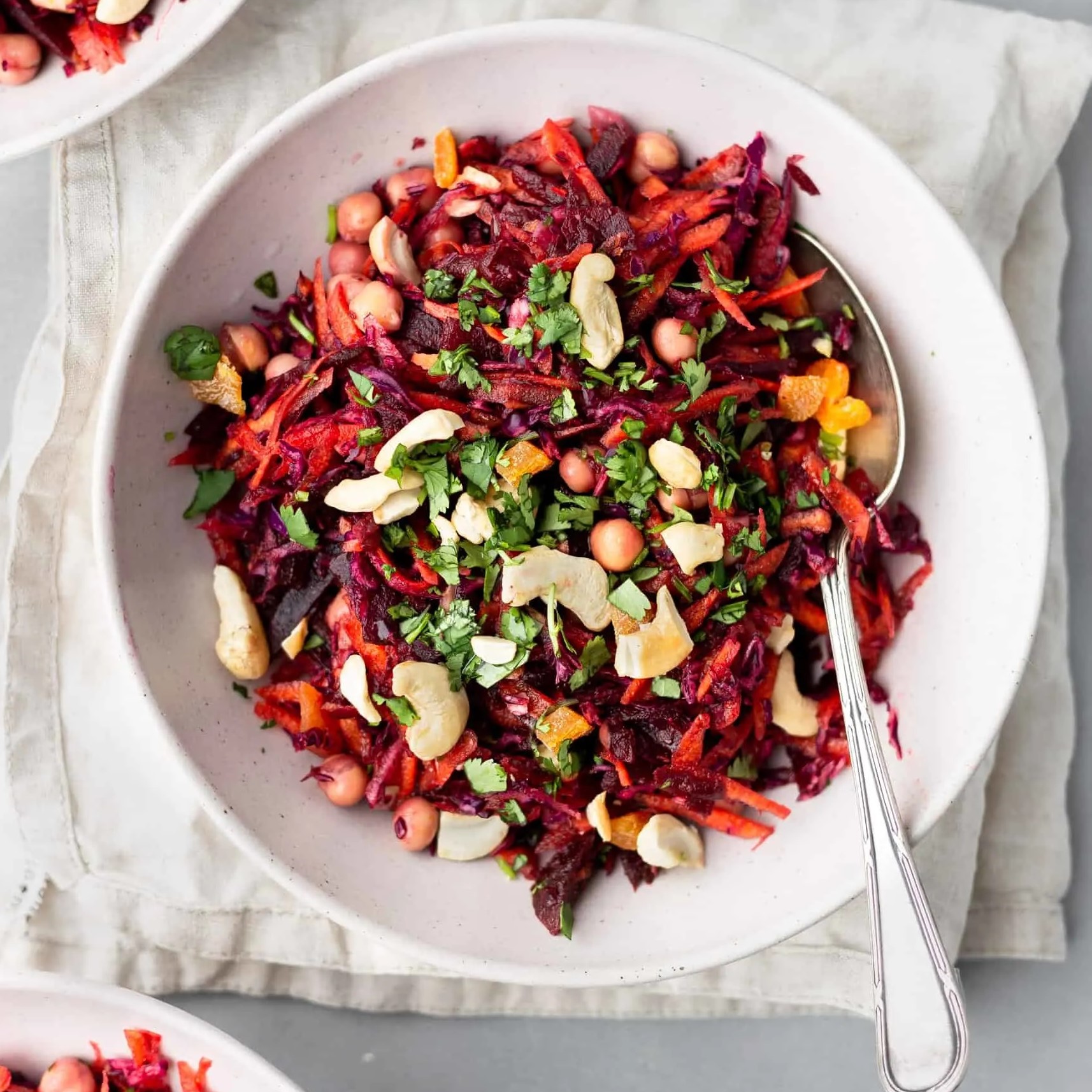 carrot, beetroot, cabbage salad in white bowl with spoon