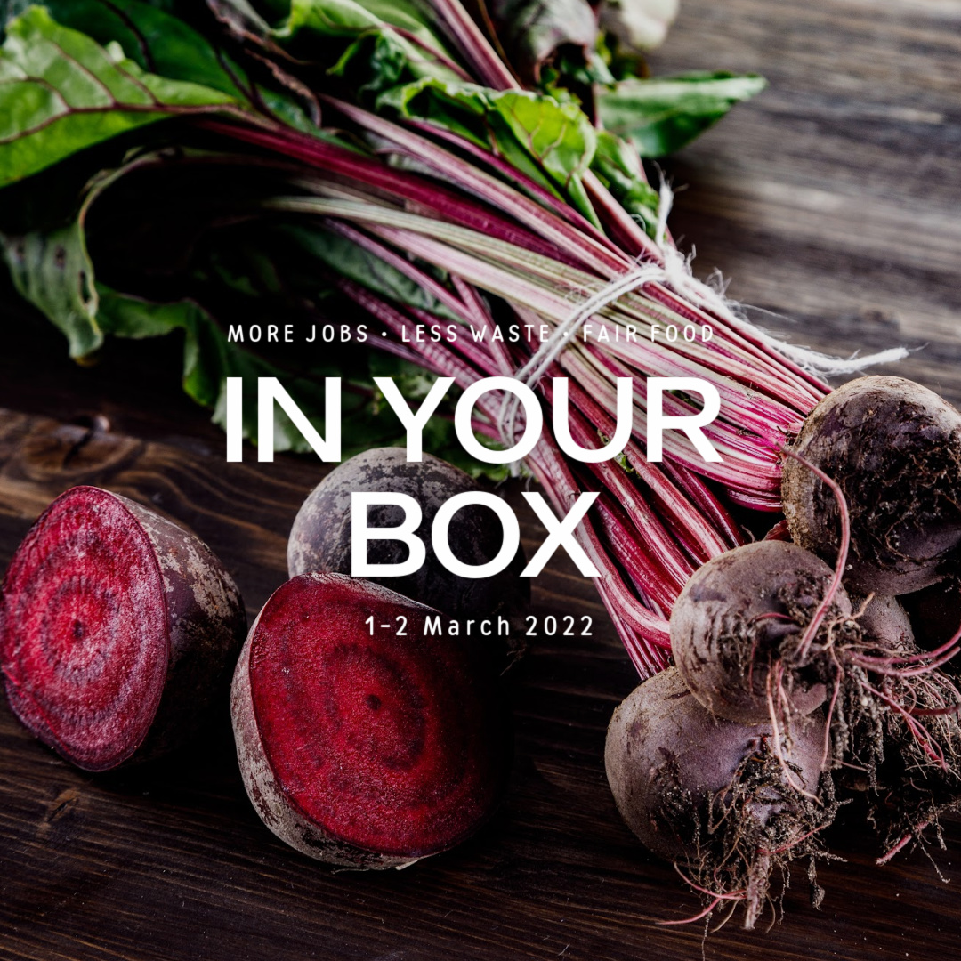 Text: 'In Your Box 1-2 March 2022', beetroots with leaves bundled together on dark wood basein background