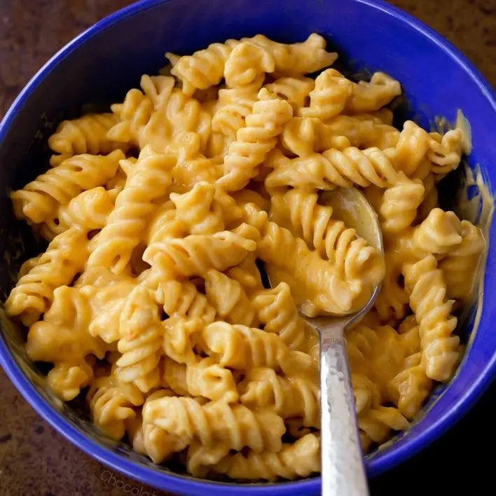 blue bowl with spiral past coated in creamy orange pumpkin sauca