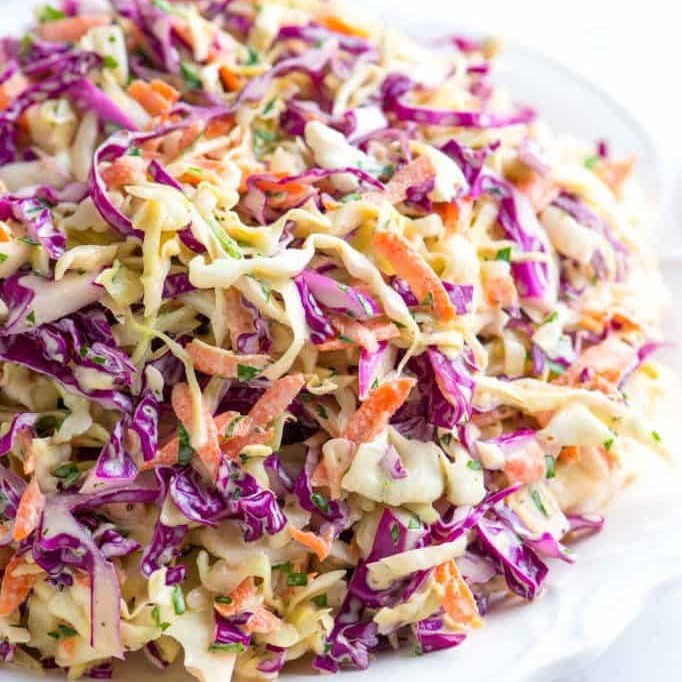 close-up of coleslaw with purple and green cabbage, carrot and parsley with light dressing