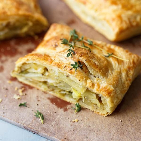rectangle puff pastry cut open so you can see that it is stuffed with thinly sliced potatoes, leeks and onions