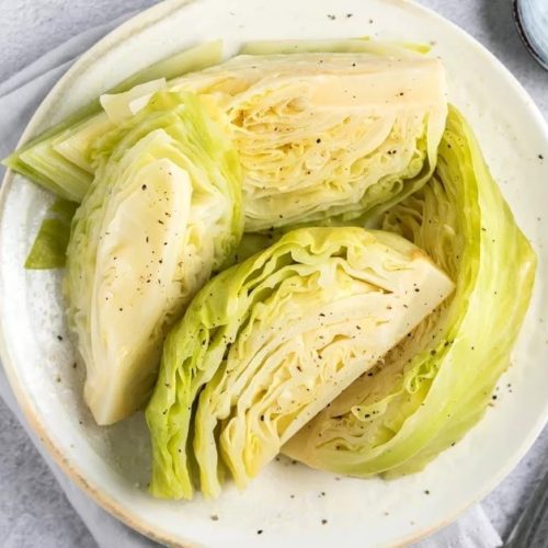 White bowl with 4 wedges of boiled green cabbage