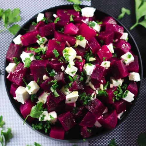 Beetroot pieces and feta with parsley in black bowl
